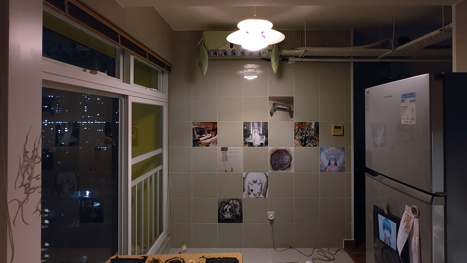 wide view of kitchen, fridge, and wall covered with stickers in tiles