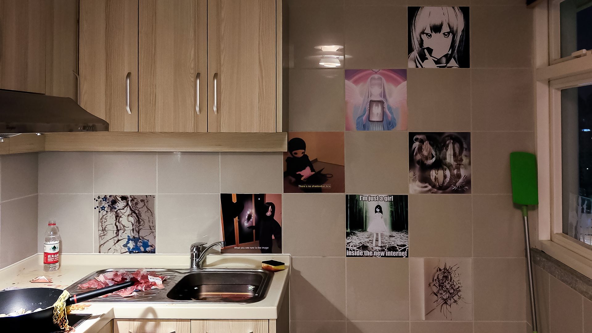 view of kitchen sink, dust cleaner and wall with several tile stickers. one says im just a girl inside the new internet. there's a denpa doll, a painting of a angel holding a device some abstract drawing and collages, some female like characters and waifu