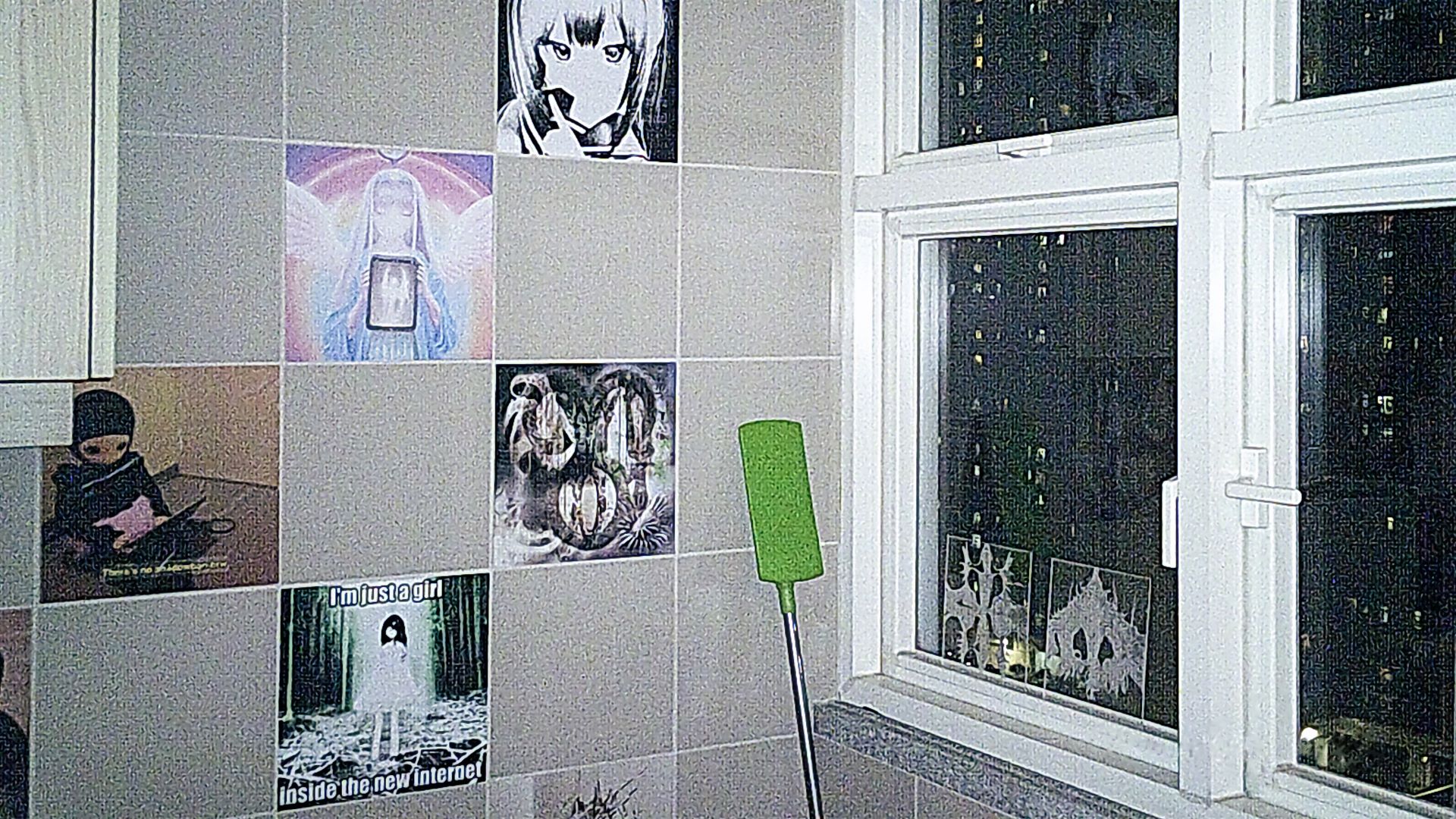 view of the kitchen wall covered with tile stickers. there's a green dust cleaner at the corner, a window with 2 transparent acrylic 1:1 tiles with abstract drawing