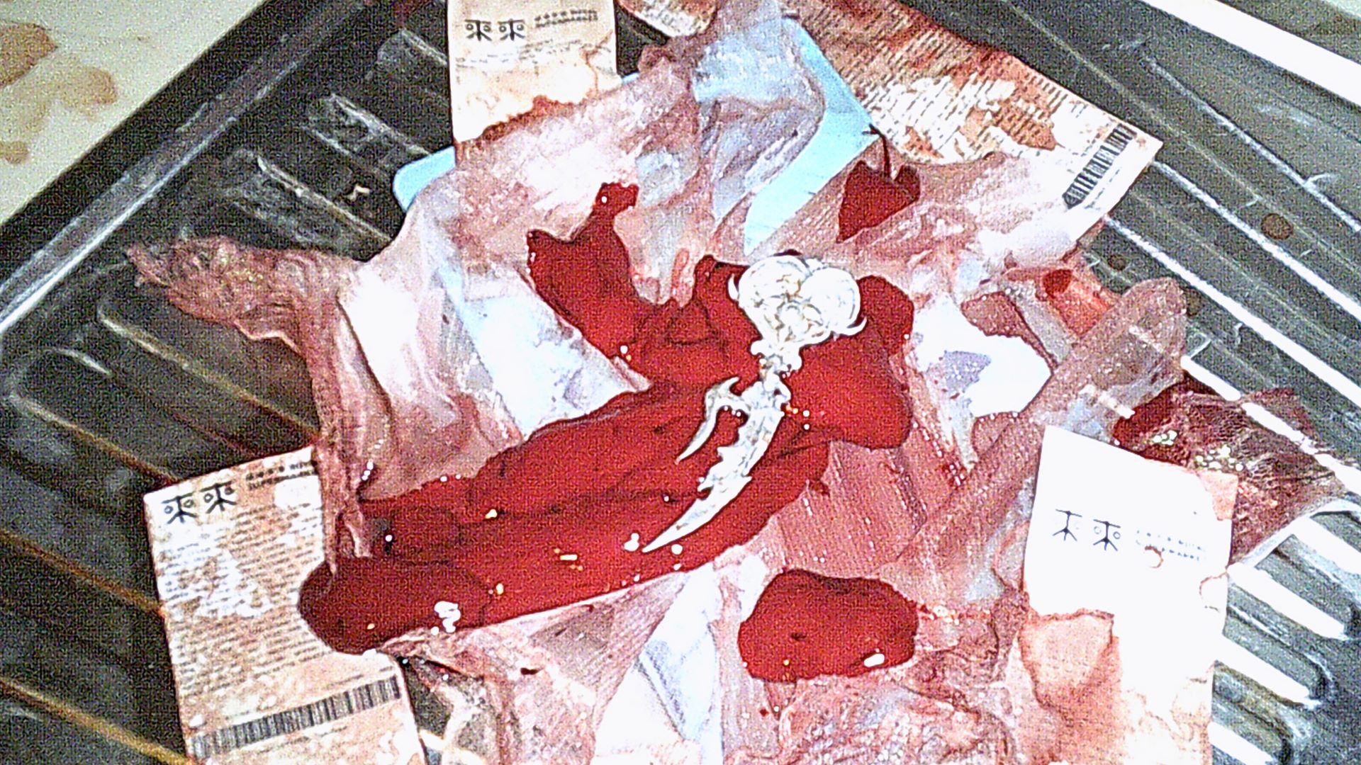 close up of mini heart sword wand laying on top of bloody liver pieces and a blue cutting board and lace and a lot of receipts from royale supermarket