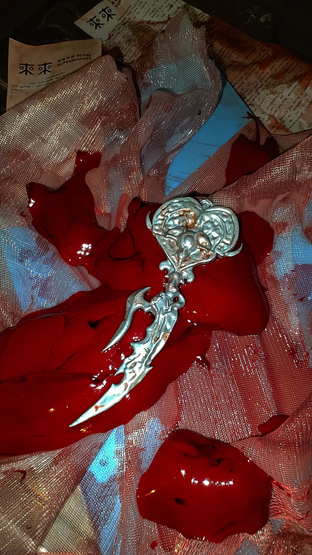 close up of the silver sword heart wand on top of red bloody liver