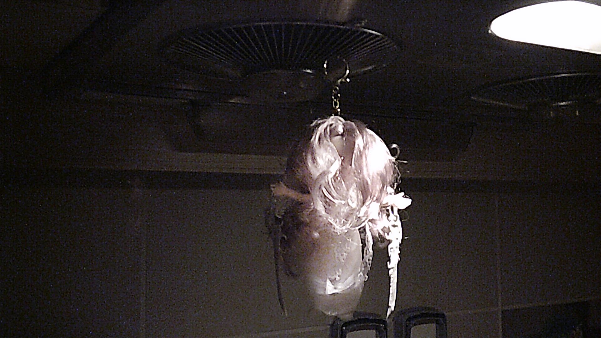 close up of doll hanging from kitchen ventilator holding two small 3d printed swords, one on each hand